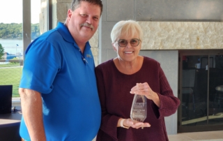 Mayor Roberts and 2022 Investor of the Year Carol Lehman are smiling at the camera. are smiling at the camera. Carol is holding a glass award.